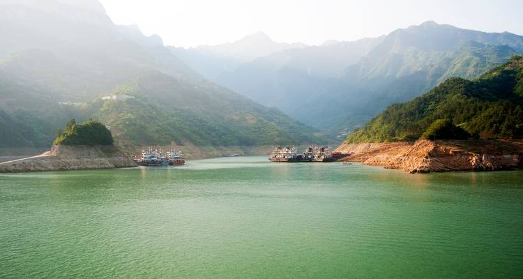 Serene groene wateren van de Drie Kloven omringd door mistige bergen en aangemeerde rivierschepen