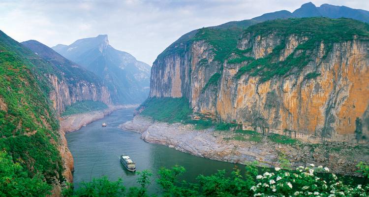 Cruiseschepen navigeren langs de dramatische kalkstenen kliffen van China's Drie Kloven langs een kronkelende rivier.