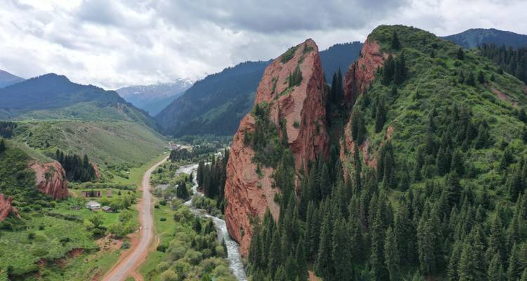 Aerial view of a valley with red rock formations and a winding river.