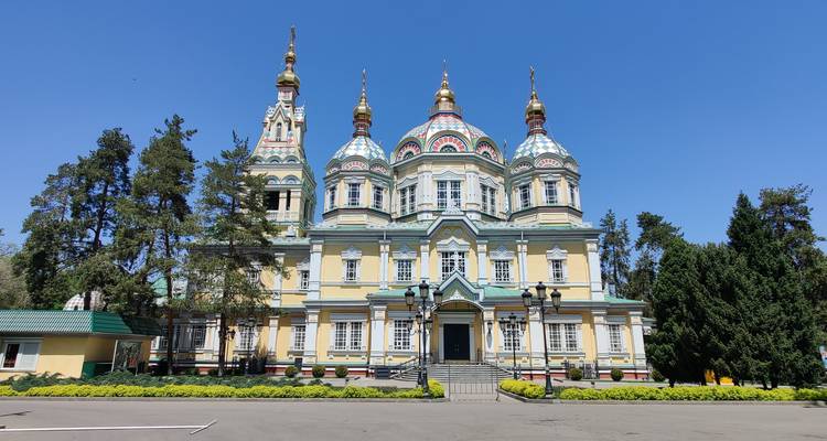 Colorful cathedral with ornate towers amidst trees.