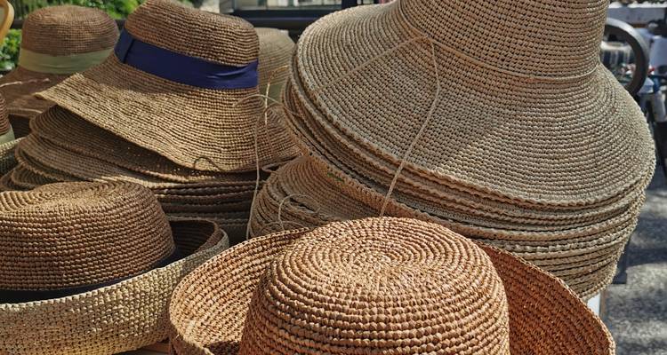 Des piles de chapeaux de paille tressée exposés.