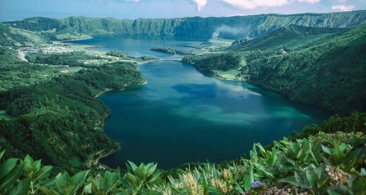 Vista panorámica de un lago de cráter exuberante rodeado de vegetación.