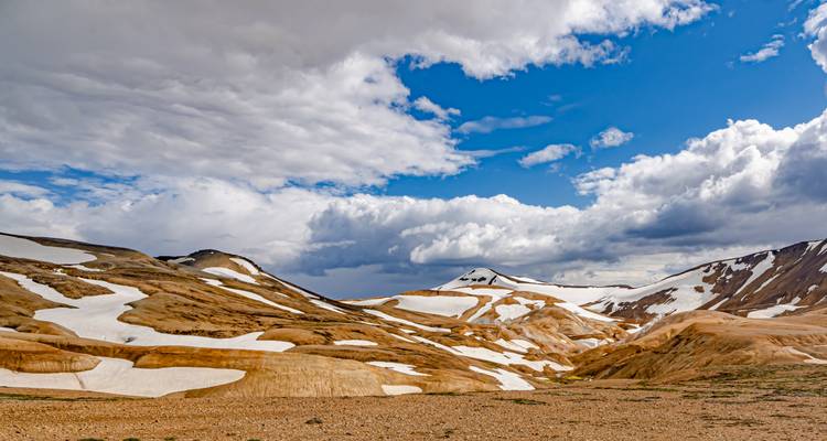 Montagnes tachetées de neige sous un ciel partiellement nuageux.