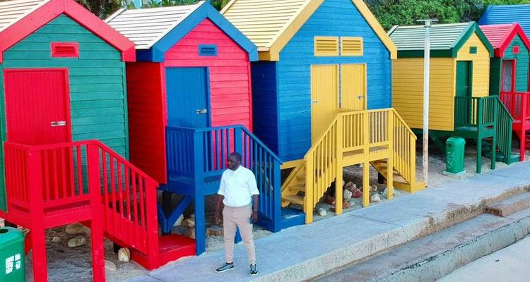 Colorful beach huts with a person standing on the pavement.