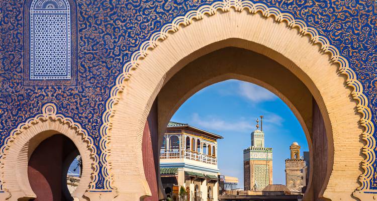 Une porte voûtée ornée avec une mosquée visible à travers celle-ci.