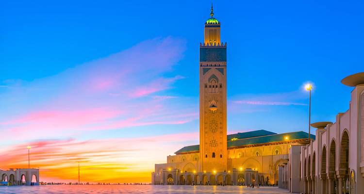Mosquée Hassan II à Casablanca au coucher du soleil avec un ciel vibrant.