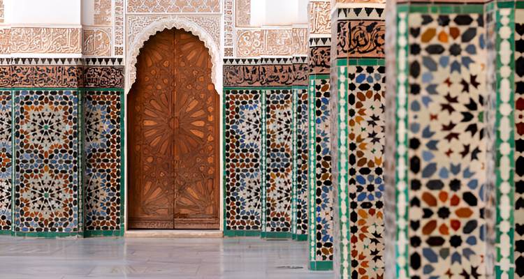 Intérieur richement décoré avec des colonnes en mosaïque et une porte en bois cintrée.