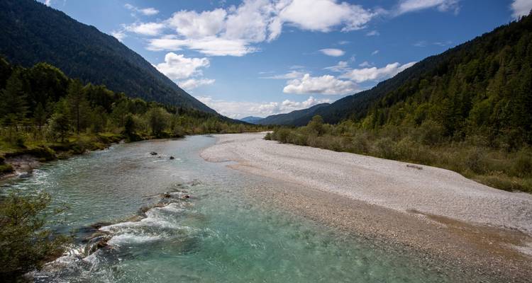 Rivière cristalline coulant à travers une vallée boisée.