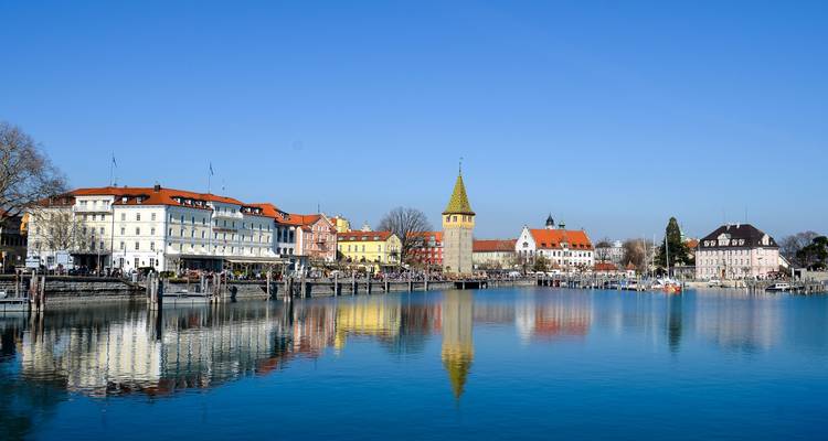 Promenade au bord du lac avec des bâtiments historiques colorés et une tour.