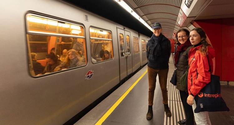Personas esperando en una plataforma de metro mientras llega un tren.