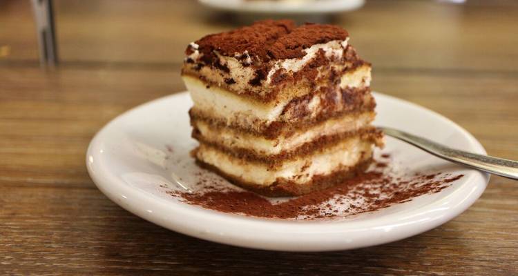 Een stuk Tiramisu op een bord met een vork.