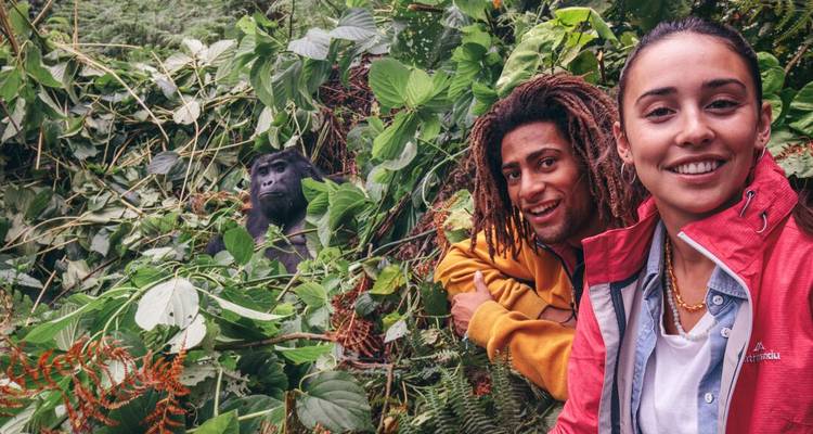 Two people taking a selfie with a gorilla in the background.