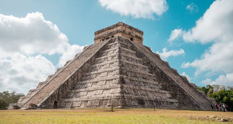 The iconic Chichen Itza pyramid under a bright blue sky.