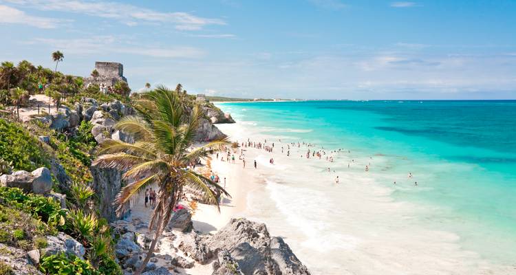 A scenic view of Tulum beach with ruins in the background.
