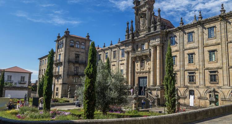A historic building surrounded by gardens and cypress trees.