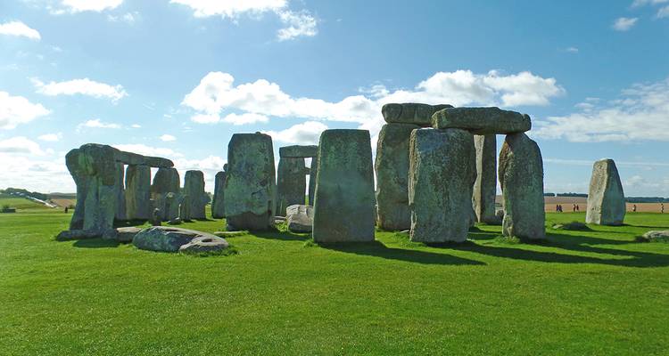 Stonehenge sous un ciel bleu vif avec des nuages épars.