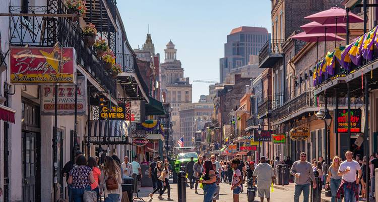 Lively street scene with people, shops, and colorful decorations in New Orleans.