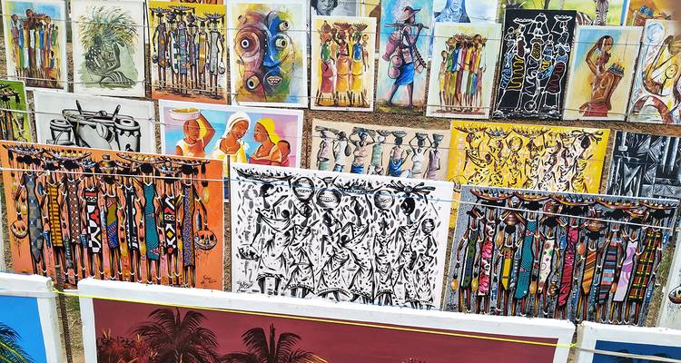 Colorful artwork displayed for sale on a wall.