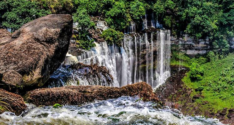 Waterfall cascading over rocks surrounded by greenery.