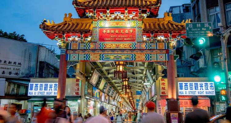 Tourists walking through a colorful night market.