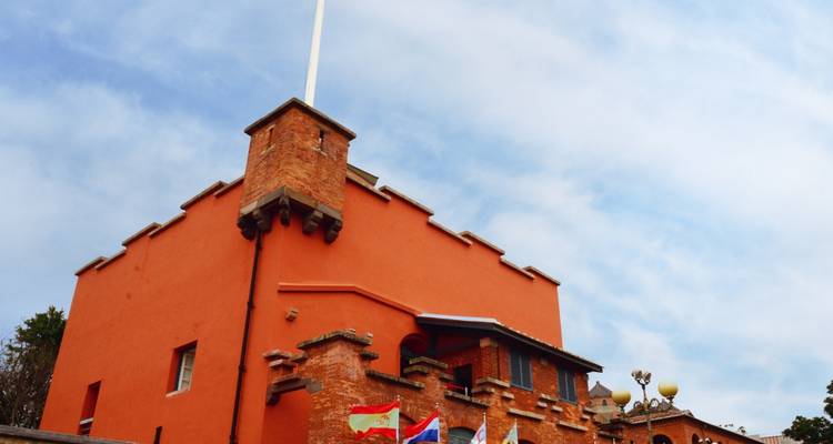 Historic brick building with flags under a cloudy sky.