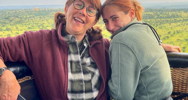 Zwei Personen lächeln in einem Korb und blicken auf eine weite Landschaft.