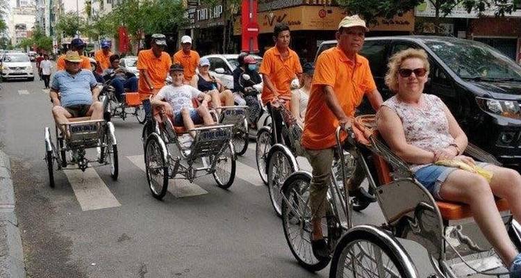 Des touristes en cyclo-pousse dans une rue animée.