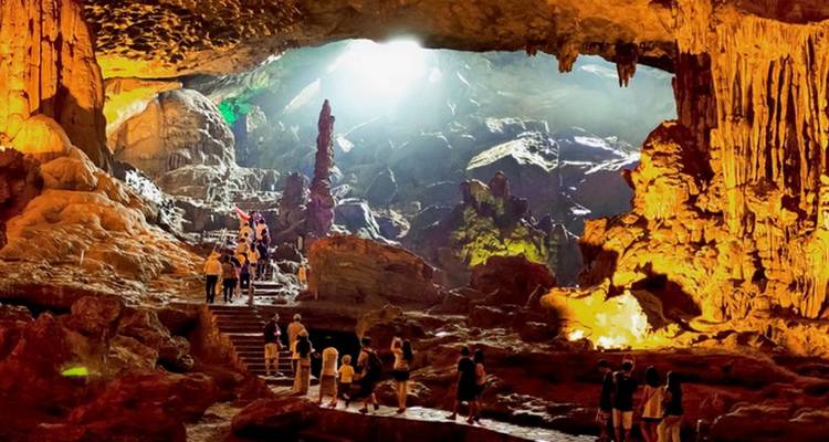 Des touristes explorent une grotte illuminée avec des stalactites.