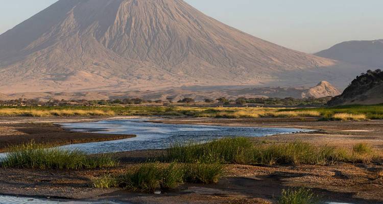 Vulkan mit einem Fluss, der durch eine grasbewachsene Landschaft fließt.