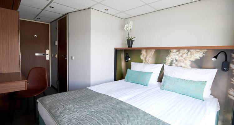 Intérieur d'une chambre d'hôtel avec lit et bureau.