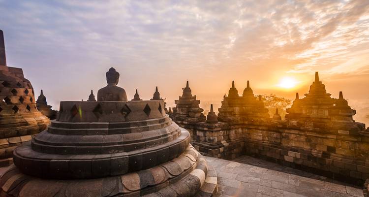 Temple de Borobudur au lever du soleil avec des stupas et une statue de Bouddha.