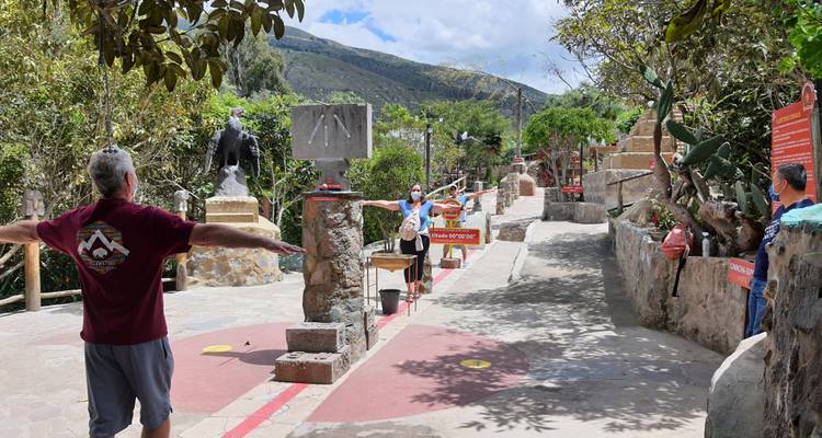 Tourists exploring a paved historical site with statues and informational signs.