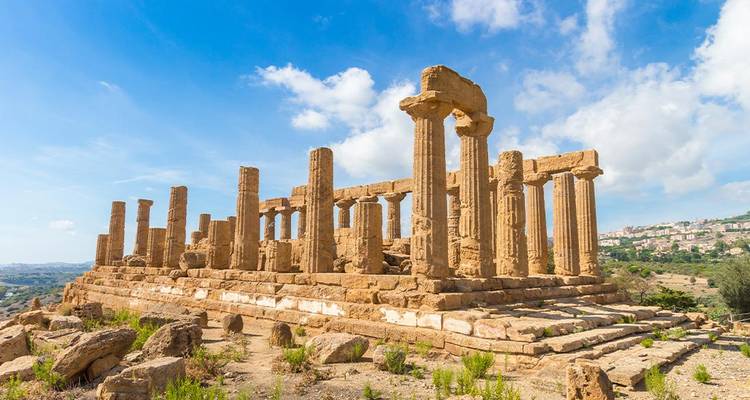 Remnants of ancient columns and buildings under a blue sky.