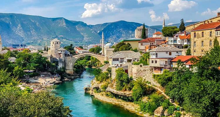 Picturesque view of a stone bridge over a river with the town in the background.