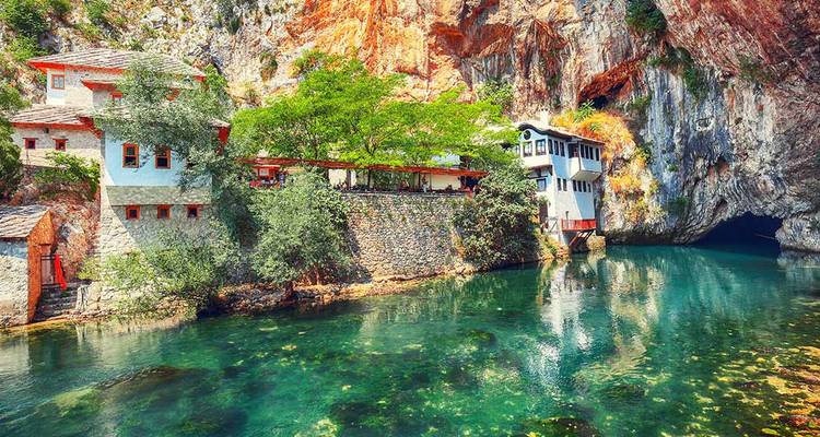 A scenic body of water with a rock face and buildings built into the landscape.