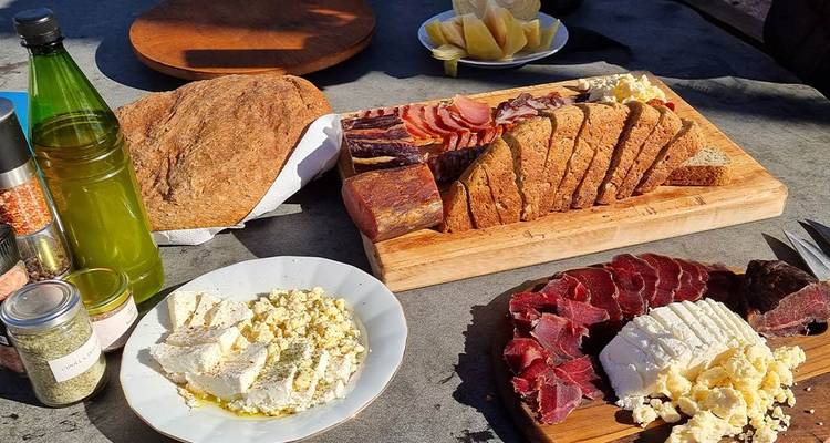 A table with an assortment of breads, meats, and cheeses.