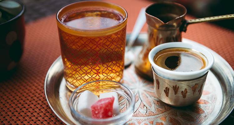 A traditional tea set with drinks and sugar cubes on a decorative tray.