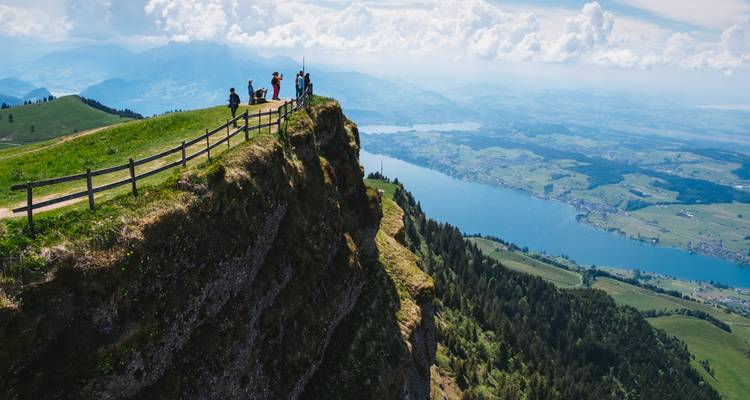 People standing on a cliff with breathtaking views of a lake and rolling hills.