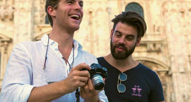 Deux hommes examinent un appareil photo devant la façade ornée d'une cathédrale gothique.