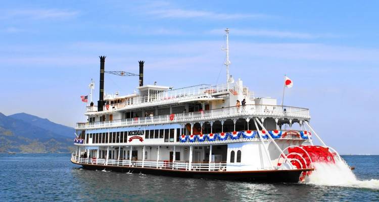 Grand bateau à vapeur à aubes avec des drapeaux sur l'eau.