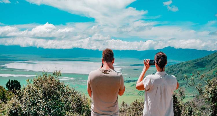 Two people observing a scenic landscape of a caldera.