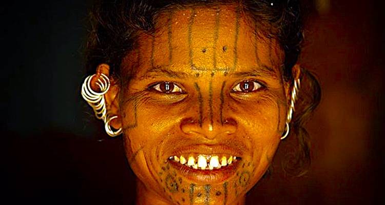 Close-up portrait of a woman with facial markings and earrings.