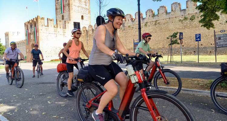 Un groupe de cyclistes roulant près d'un mur historique.