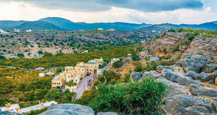 Vallée avec des maisons et terrain rocheux avec des montagnes.