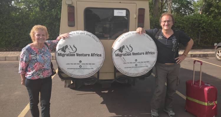 Deux personnes debout à côté d'un véhicule de safari avec marquage.