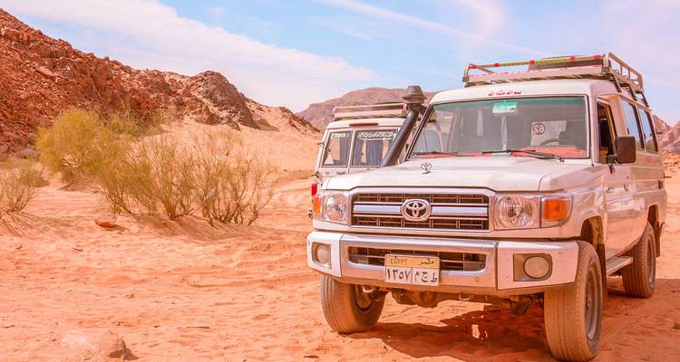 Véhicules tout-terrain stationnés dans un décor désertique.