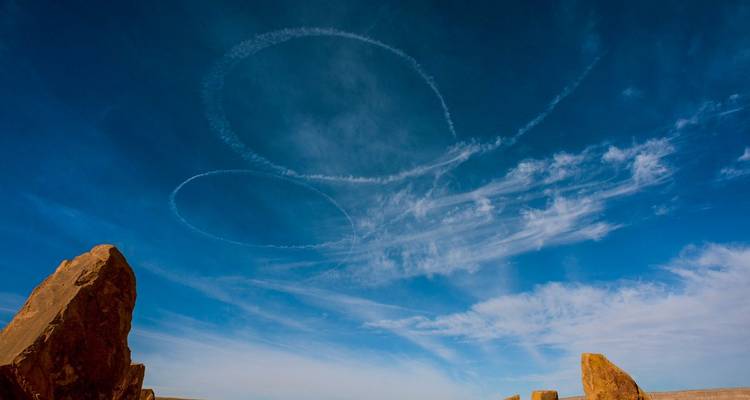 Ciel bleu limpide avec des motifs nuageux artistiques au-dessus d'un paysage désertique.