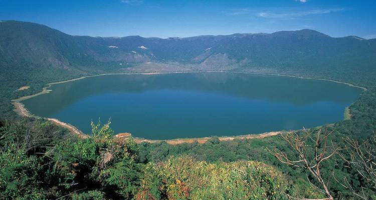Grand lac de cratère entouré de montagnes et de forêt.