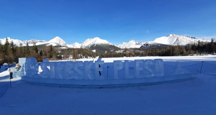 Sculpted snow sign with mountain range in the background.