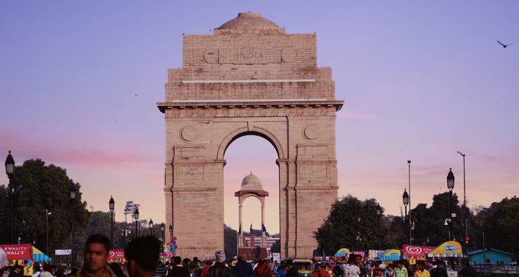 India Gate with people and a pink sunset sky.